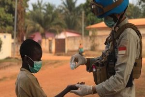 A peackeeper from the UN Multidimensional Integrated Stabilization MIssion in the Central African Republic (MINUSCA) sanitizes a little boy's hands.